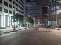 this empty street is at night with lots of buildings in the background while no one can tell