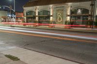 an empty city street at night with a red fire hydrant and a white building