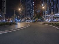 empty city street in front of tall buildings at night with blue lights reflected on the wall