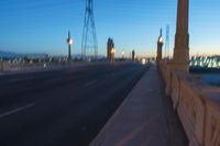 a city street that is empty at night with lights shining on it at sunset near a bridge