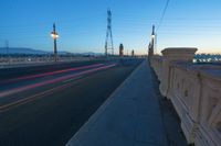 a city street that is empty at night with lights shining on it at sunset near a bridge