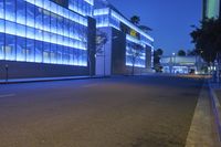 a empty city street at night with tall buildings in the background with lights on in the middle