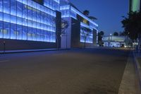 a empty city street at night with tall buildings in the background with lights on in the middle