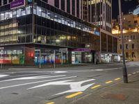 the street that is empty in the city at night time with an arrow sign on it