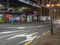 the street that is empty in the city at night time with an arrow sign on it