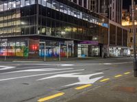 the street that is empty in the city at night time with an arrow sign on it