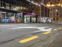 the street that is empty in the city at night time with an arrow sign on it