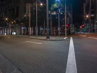 an empty city street at night with a traffic signal light above it and a few palm trees