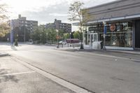 an empty city street with some stores on the side of it and a parking lot next to it