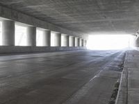 an empty city street is shown at an overpass, with two long sections of concrete and windows on either side