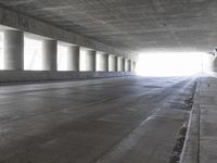 an empty city street is shown at an overpass, with two long sections of concrete and windows on either side