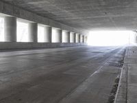 an empty city street is shown at an overpass, with two long sections of concrete and windows on either side