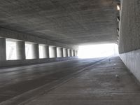 an empty city street is shown at an overpass, with two long sections of concrete and windows on either side