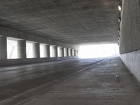 an empty city street is shown at an overpass, with two long sections of concrete and windows on either side