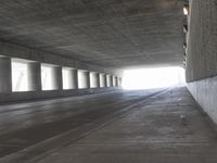 an empty city street is shown at an overpass, with two long sections of concrete and windows on either side