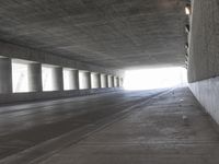 an empty city street is shown at an overpass, with two long sections of concrete and windows on either side