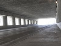 an empty city street is shown at an overpass, with two long sections of concrete and windows on either side