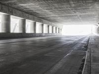 an empty city street is shown at an overpass, with two long sections of concrete and windows on either side