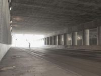 an empty city street is shown at an overpass, with two long sections of concrete and windows on either side