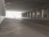 an empty city street is shown at an overpass, with two long sections of concrete and windows on either side