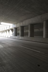 an empty city street is shown at an overpass, with two long sections of concrete and windows on either side