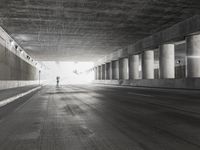 an empty city street is shown at an overpass, with two long sections of concrete and windows on either side