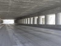 an empty city street is shown at an overpass, with two long sections of concrete and windows on either side