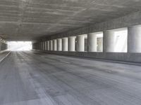 an empty city street is shown at an overpass, with two long sections of concrete and windows on either side