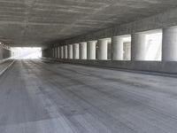 an empty city street is shown at an overpass, with two long sections of concrete and windows on either side