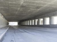 an empty city street is shown at an overpass, with two long sections of concrete and windows on either side