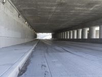 an empty city street is shown at an overpass, with two long sections of concrete and windows on either side