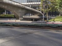 an overpass on an otherwise empty city street, with cars parked and people standing underneath