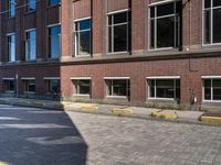 the corner of an empty city street is made from red brick, with yellow border