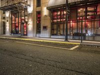 an empty city street at night with red lights and windows and the street lined with street lights