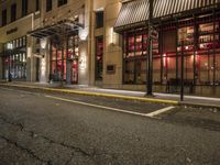 an empty city street at night with red lights and windows and the street lined with street lights