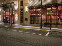 an empty city street at night with red lights and windows and the street lined with street lights