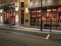 an empty city street at night with red lights and windows and the street lined with street lights