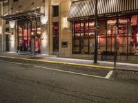 an empty city street at night with red lights and windows and the street lined with street lights