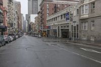 an empty city street with cars and building on either side of the road on a rainy day