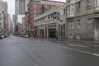an empty city street with cars and building on either side of the road on a rainy day