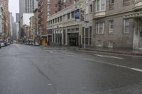 an empty city street with cars and building on either side of the road on a rainy day