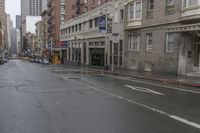 an empty city street with cars and building on either side of the road on a rainy day