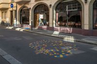 an empty city street is painted with dots in the road as well as buildings and people