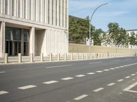 an empty city street with two tall buildings in the background of it and a person walking on one of the side of the sidewalk