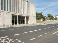 an empty city street with two tall buildings in the background of it and a person walking on one of the side of the sidewalk