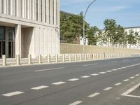 an empty city street with two tall buildings in the background of it and a person walking on one of the side of the sidewalk