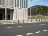 an empty city street with two tall buildings in the background of it and a person walking on one of the side of the sidewalk