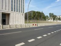 an empty city street with two tall buildings in the background of it and a person walking on one of the side of the sidewalk