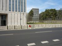 an empty city street with two tall buildings in the background of it and a person walking on one of the side of the sidewalk