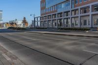 an empty city street and large buildings in the background as seen from the side of the road